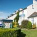 The Parks Guest House in Minehead, exterior view with white facade, garden hedges and sign