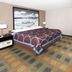 Super 8 by Wyndham Keokuk guest room with king bed, armchair, and colorful carpet