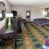 Super 8 by Wyndham Keokuk guest room with two beds, desk, armchair and plaid carpet