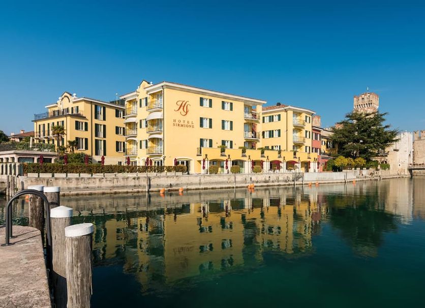 Hotel Sirmione Terme in Sirmione beside the waterfront, with buildings reflected in calm water
