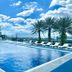 Le Charme Suites Subic in Olongapo: outdoor pool with lounge chairs, palm trees and mountain views