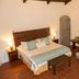 Hotel La Villa Serena in Antigua guest room with wooden bed, tiled floor, fireplace, and arched wall decor