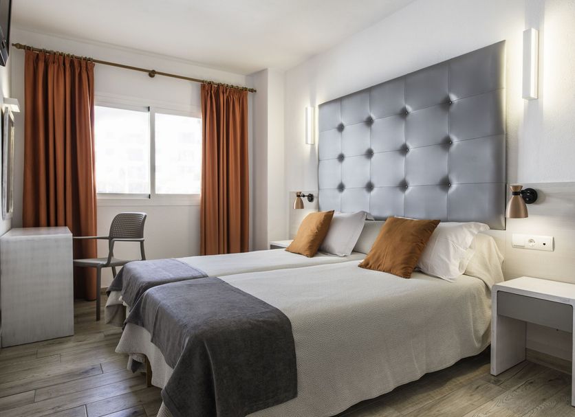 Bedroom at Apartamentos Oasis Sa Tanca in Santa Eulària des Riu with twin beds, large tufted headboard and window seating