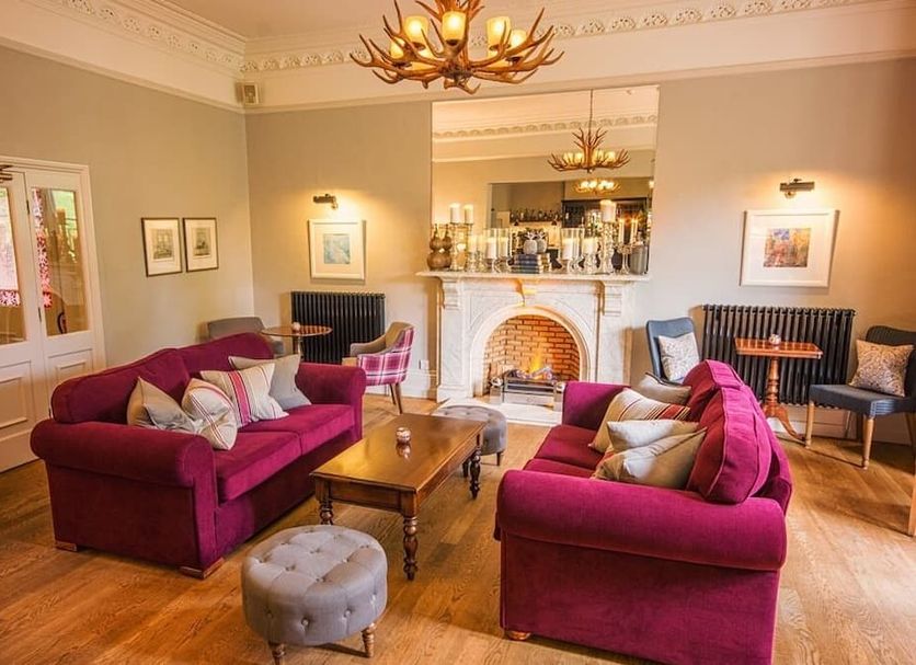 Eslington Villa, Gateshead: elegant lounge with magenta sofas, fireplace, wood floors and chandelier
