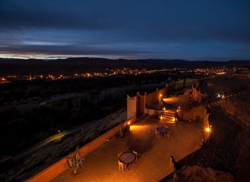 Kasbah Tizzarouine in Boumalne Dadès with a lit terrace overlooking a valley at night