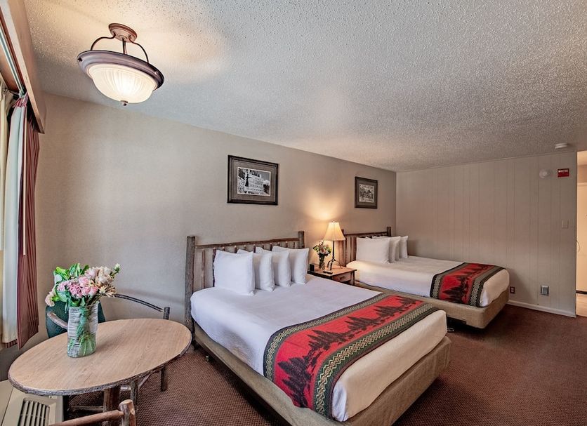 Antler Inn in Jackson guest room with two beds, bedside lamp, and small table with flowers