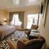 Mannah Executive Guestlodge in Kempton Park bedroom with king bed, armchair, patterned rug and window