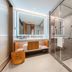 Dongguan Huaxi International Hotel bathroom with glass shower, large vanity mirror, and woven basket in Dongguan