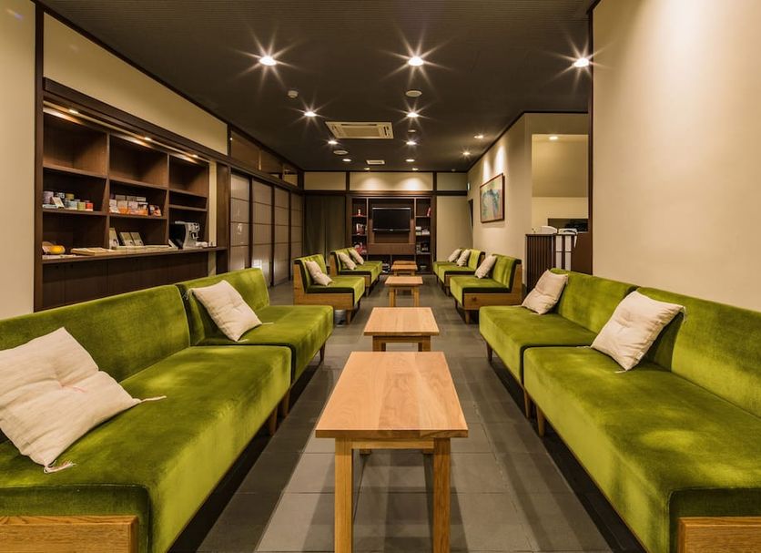 Ryokan Ryokufuso Kyoto lounge with green sofas, wooden tables, and recessed ceiling lights