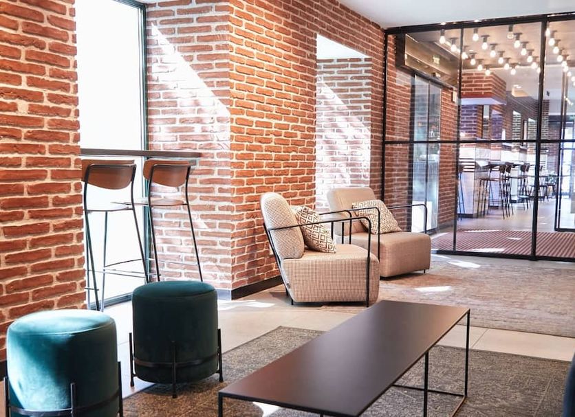 Latroupe Prado in Madrid lobby seating area with brick walls, bar stools, armchairs and glass doors