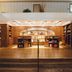 Emeline Charleston lobby with wood-paneled reception desk, mezzanine railing, and warm lighting