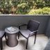 Balcony seating area at Sun City Hotel in Tel Aviv with two chairs and a small table overlooking trees.