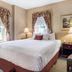 Traditions Hotel & Spa Johnson City guest room with king bed, bedside lamp, chair and window views