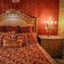 Olympia Villas in Stoupa: ornate red-and-gold bedroom with carved headboard and matching bedside tables