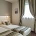 Relax Hôtel Beuzeville Honfleur room with two single beds and striped bedding by a window in Honfleur