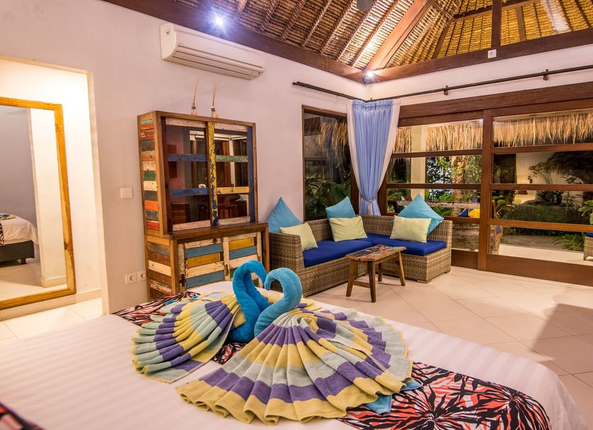 Bali Santi Bungalows in Manggis, bedroom with swan towel art and seating area under a thatched roof