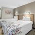 Red Roof Inn Dayton North Airport room with two beds, chair, vanity and wall art in Dayton