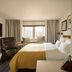 The Nikolai Hamburg room with king bed, armchair, desk and large window view in Hamburg