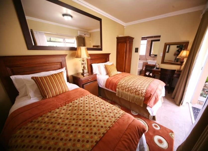 Le Cozmo Guest House in Alberton, twin beds in a warmly lit guest room with balcony access