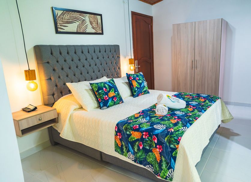 Villeta Resort Hotel in Villeta bedroom with tufted headboard, floral bedding, bedside lamps, and wardrobe