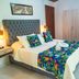 Villeta Resort Hotel in Villeta bedroom with tufted headboard, floral bedding, bedside lamps, and wardrobe