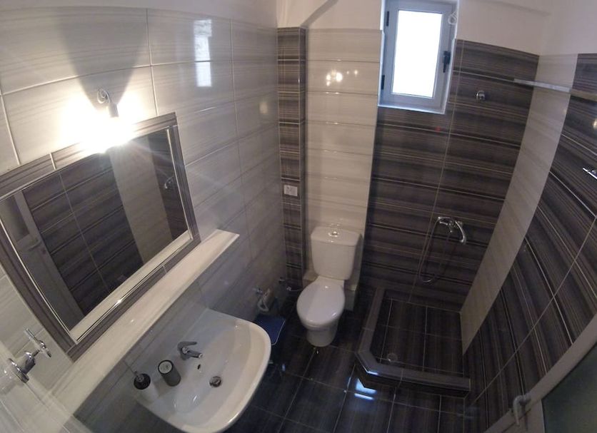 Riviera Rooms Himarë bathroom with sink, toilet, window, and tiled shower