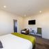 Harvest Lodge Hastings room with king bed, wall-mounted TV, chair and small table