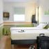 Ibis Budget Givet guest room with twin beds, wall-mounted TV, window, and luggage in Givet