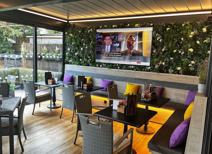 The Carrington Arms, Newport Pagnell: covered outdoor dining area with TV, tables and colorful cushions