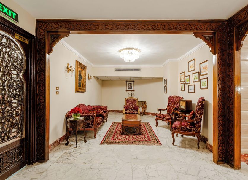 Om Kolthoom Hotel Cairo lobby with ornate woodwork, red patterned seating and marble floor