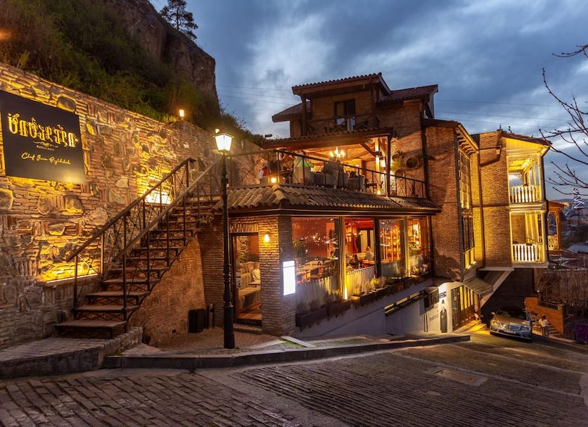 Hotel Citadel Narikala in Tbilisi, illuminated hillside hotel with terraced balconies at dusk