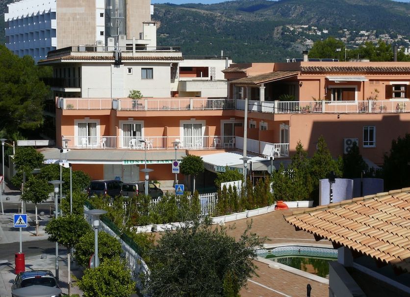 Hostal Jakiton in Magaluf with peach-colored buildings and mountain views behind the property.