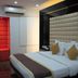 Sri Nanak Continental Hotel New Delhi guest room with king bed, tufted headboard, and red accent wall