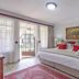 Afrique Boutique Hotel O.R. Tambo guest room with king bed, red accents, balcony doors and forest artwork in Boksburg