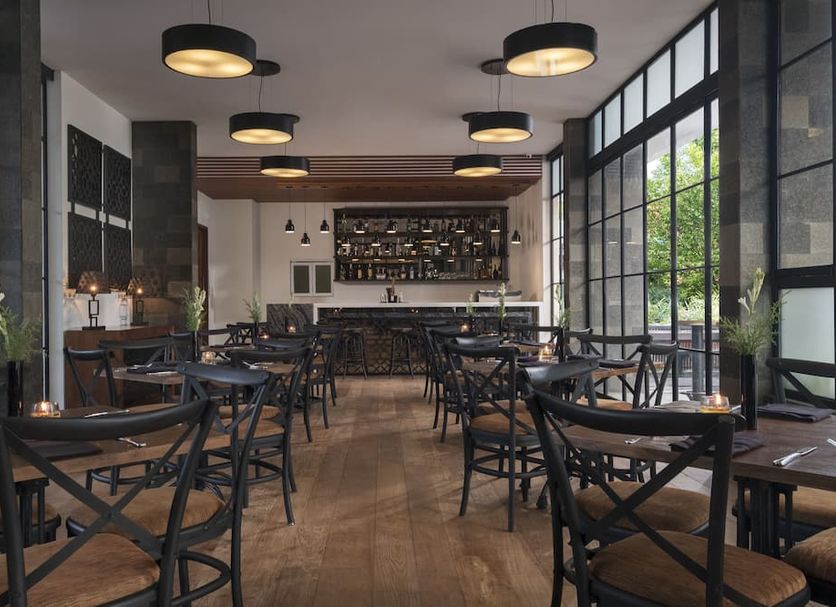 Akana Boutique Hotel Denpasar restaurant interior with black tables, bar, and large windows