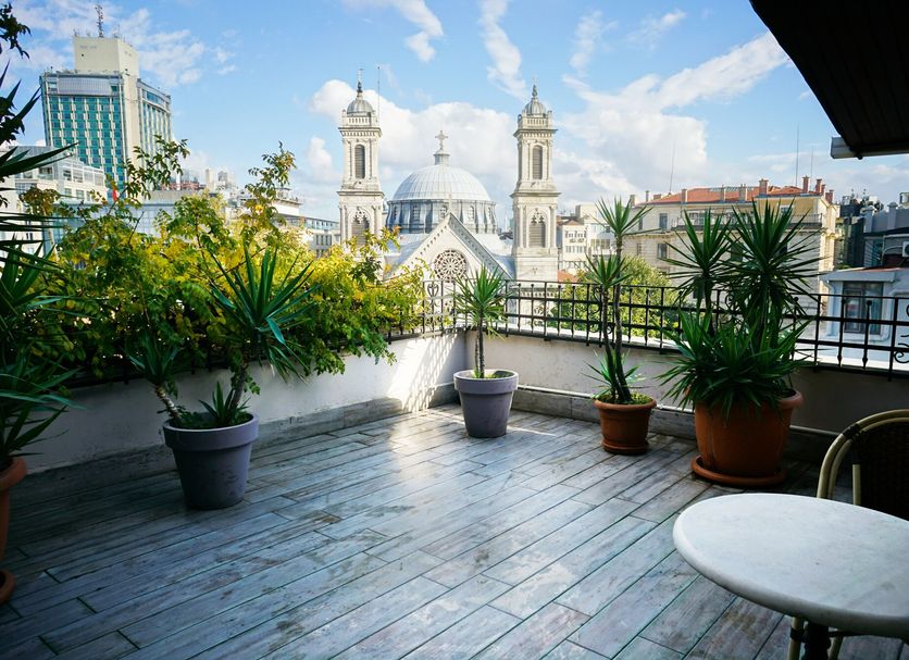 Terrace at Triada Hotel Taksim in Istanbul with potted plants and city views of a domed mosque