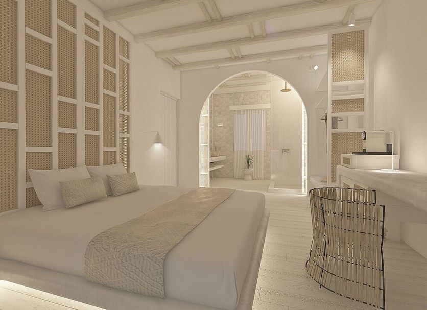 Petri Suites in Agios Georgios features a serene bedroom with arched doorway and woven chair