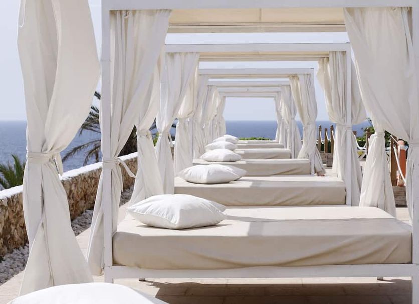 Hotel Palia Maria Eugenia in Cales de Mallorca: beachfront cabana beds with white curtains and sea view