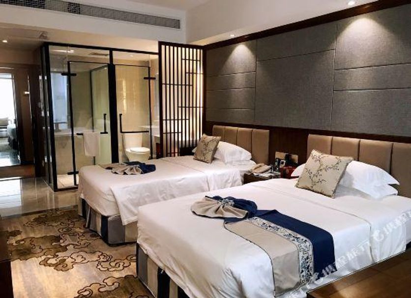 Zhangzhou Yinjia Hotel (Gucheng Branch) guest room with two beds and glass-enclosed bathroom in Zhangzhou