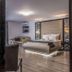 Prestige Deluxe Hotel Aquapark Club in Golden Sands: modern guest room with king bed, seating area and glass walls