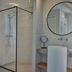 WestCord Hotel de Wadden in Oost-Vlieland bathroom with walk-in shower, round mirror and vessel sink