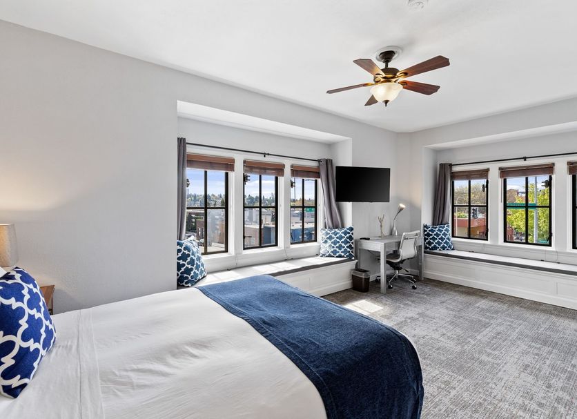 College Inn Hotel Seattle guest room with bed, desk, ceiling fan and large windows