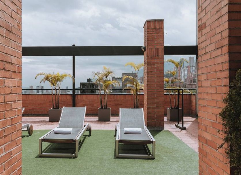 Travelers Orange Suites in Medellín rooftop terrace with loungers and city views