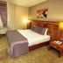 Adana Garden Business Hotel guest room with double bed, bedside lamps, desk and chairs in Adana