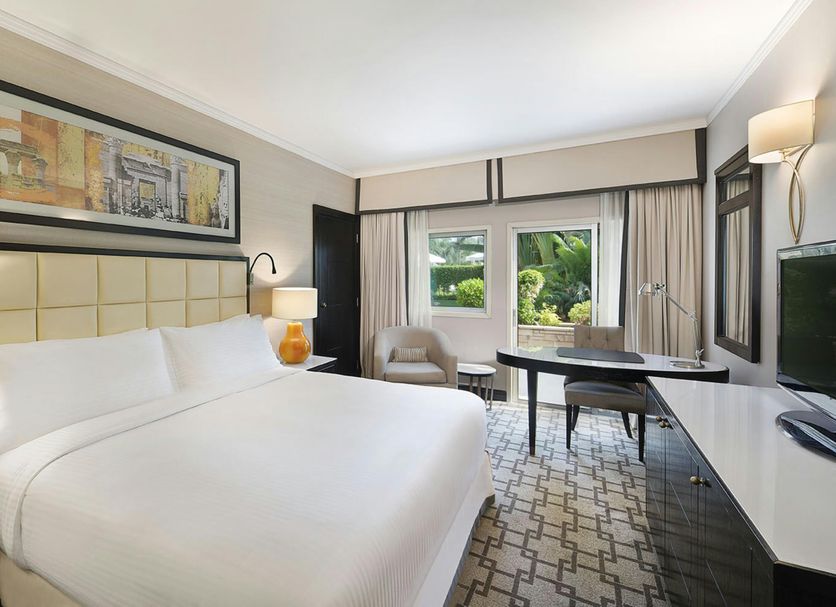 Hilton Cairo Heliopolis room in Cairo with king bed, desk, and large window overlooking greenery