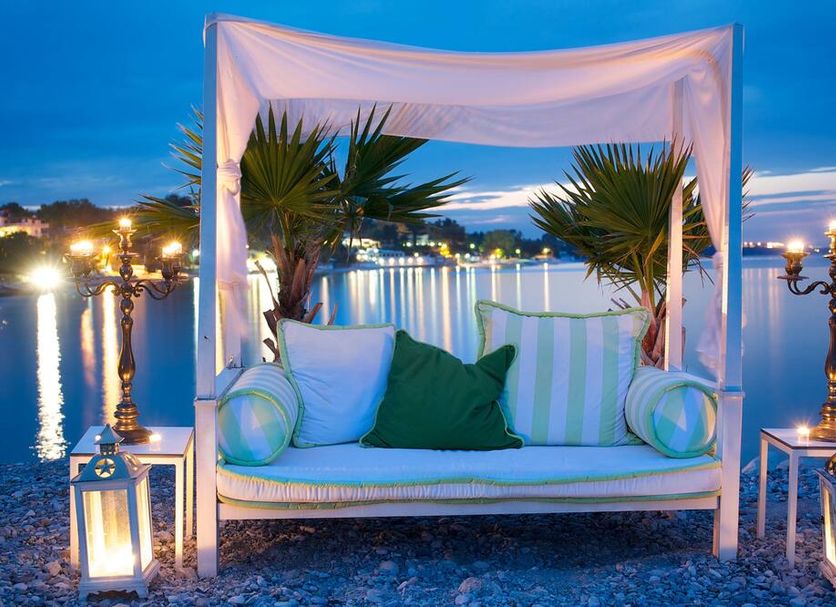 Litohoro Olympus Resort Villas & Spa in Kateríni: lakeside canopy daybed with lanterns at sunset