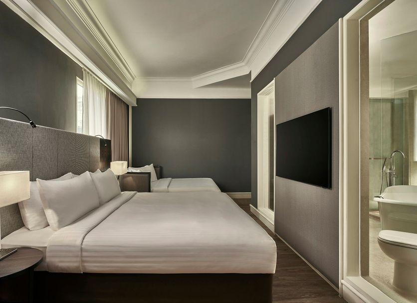 Vibe Hotel Singapore Orchard guest room with twin beds, wall-mounted TV and bathroom view