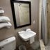 The 409 Bolivar Beach Hotel bathroom with sink, mirror, toilet, and tiled shower in Bolivar Peninsula