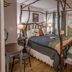 Country Woods Inn Glen Rose rustic four-poster bedroom with painted bed, wood floors, and countryside mural