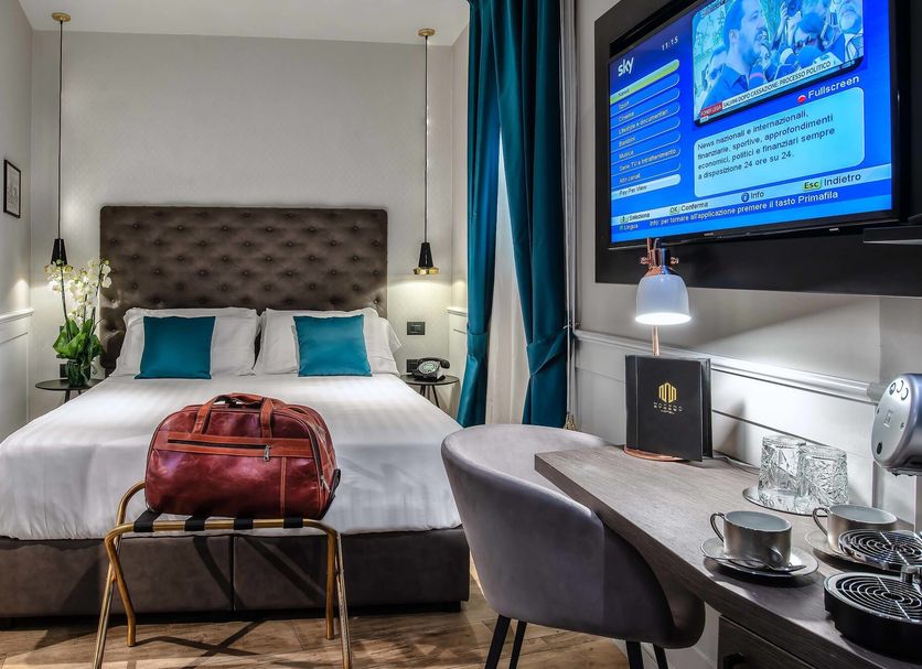 Navona Street Hotel Rome guest room with king bed, desk, wall TV and blue curtains